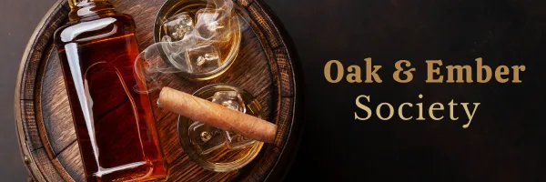 Oak & Ember Society header: a bottle of bourbon, two glasses and a cigar on a barrel
